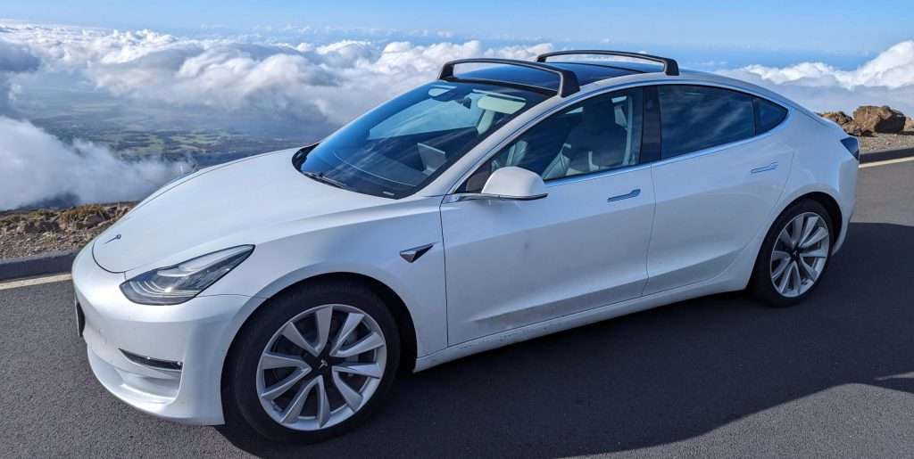 Tesla Model 3 on Haleakala with the backdrop of clouds and the valley below