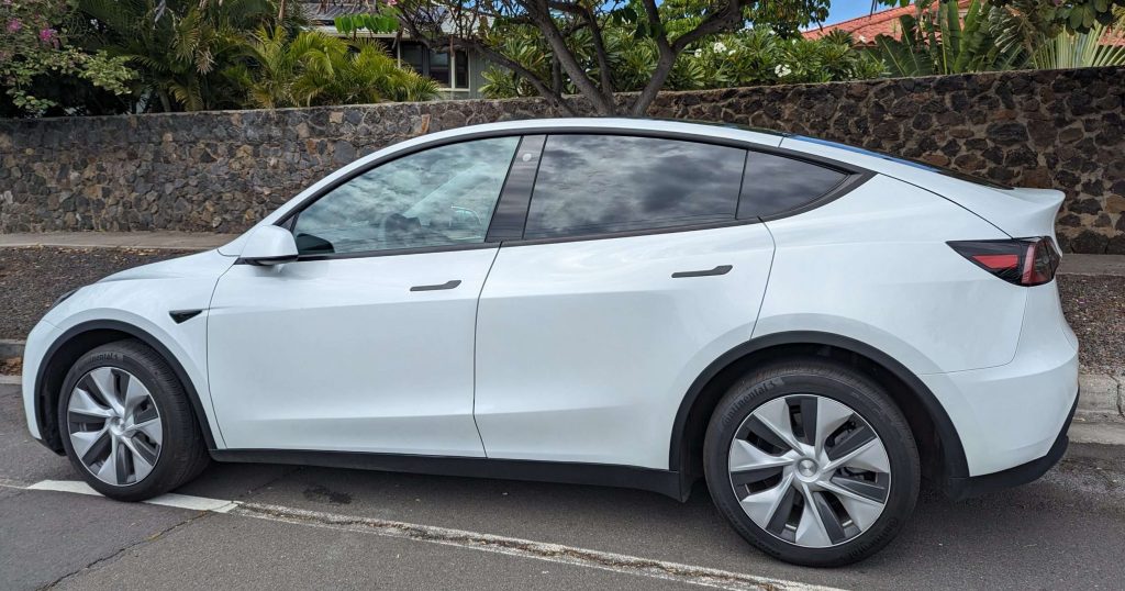Tesla Model Y parked in front of a stone wall